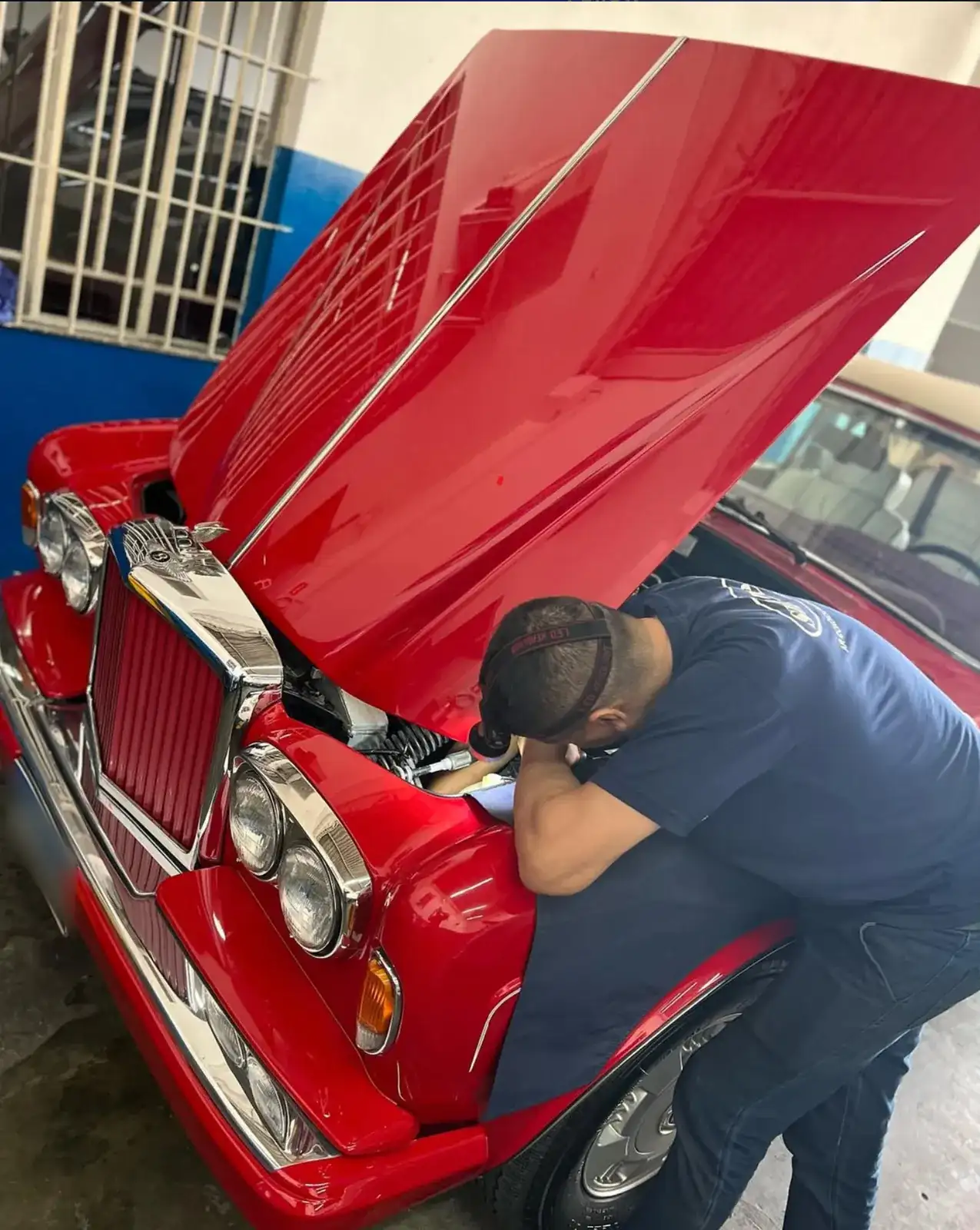 Mecânico da Subzero trabalhando no motor de um Bentley clássico vermelho com o capô aberto